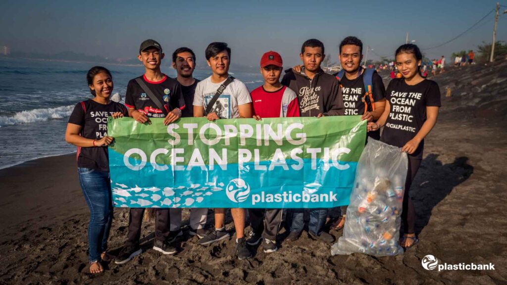 Acht junge Menschen die Müll vom Strand gesammelt haben mit einer Banderole Stopping Ocean Plastic für die Umwelt die vom Umzugsunternehmen USD Umzüge unterstützt werden