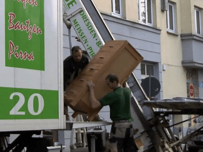 2 Männer beladen einen LKW von USD Umzüge mit einem Schrank aus Holz